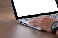 Close-up of a hand using a laptop with a blank screen, ideal for adding custom content.